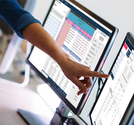 A hand pointing to a group of digital monitors displaying Altair Monarch software UI screens.