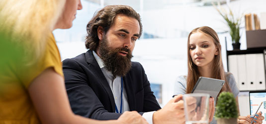 Three people in an office looking at a tablet.