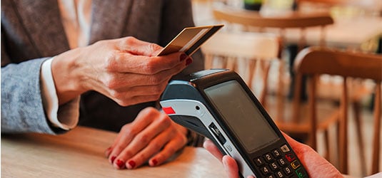 Person handing a bank card to another person.