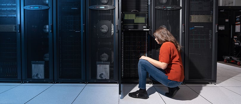 Woman in a server room inspecting equipment