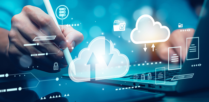 Hand holding a stylus, poised over a tablet and laptop, overlaid with illustrations of cloud computing uploads and downloads.