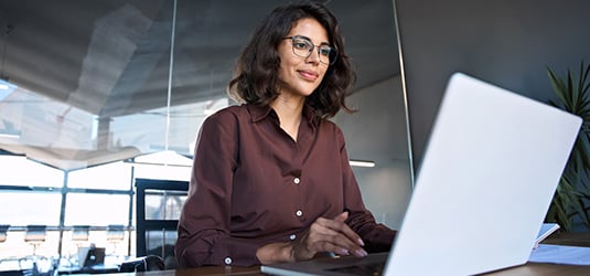 Person with glasses on laptop using AI agents.