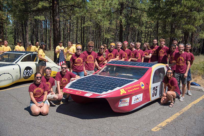 An photo of Kory Soukup's solar vehicle team posed around their solar vehicle.