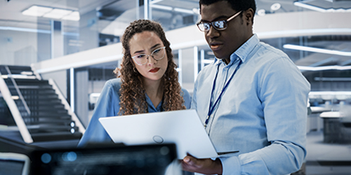 Two professionals looking at HPC and cloud reporting on a laptop in a technical business setting.