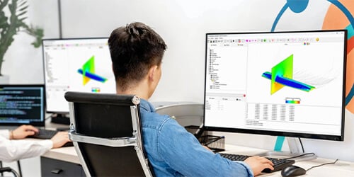 Engineer using FlightStream aerodynamic simulation software on a desktop computer.