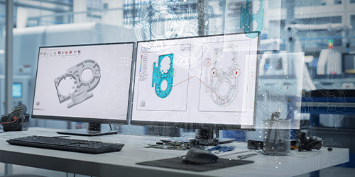 Twin workstation screens in a factory showing design of cast metal part plus AI exploration to compare, refine, and accelerate design decisions.