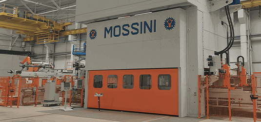 Stamping press for manufacturing; exterior is orange and white with name MOSSINI on side; some press hydraulics are exposed.